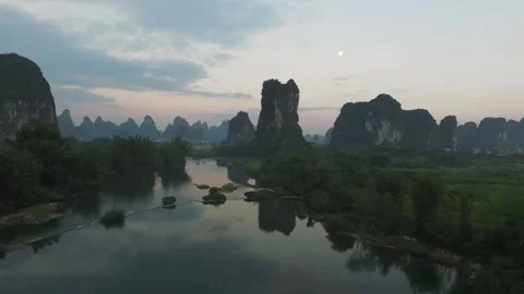 Tranquil river reflecting mountains under a twilight sky with the moon Stock Footage 311819826