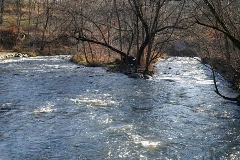 Tranquil river stream splits towards waterfall in early morning winter Фото
