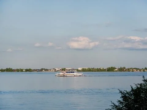A tranquil river view with a ship in the distance and calm water under a cl.. Stock Photos