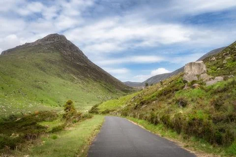 A tranquil road winds gracefully through vibrant green hills in Silent Valley Foto stock