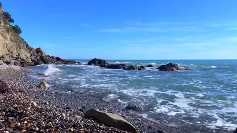 Tranquil rocky coastline with waves under clear blue summer sky Stock Footage 310245947
