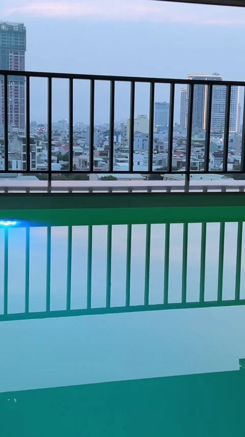 A tranquil rooftop infinity pool reflects the vibrant colors of a stunning Stock Footage 307989695