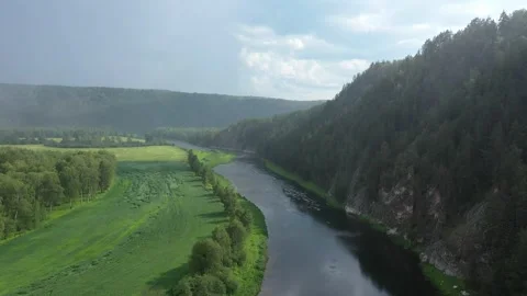 Tranquil scene of clean river among green field and rocky mountain during rain Vídeo Stock 254350919
