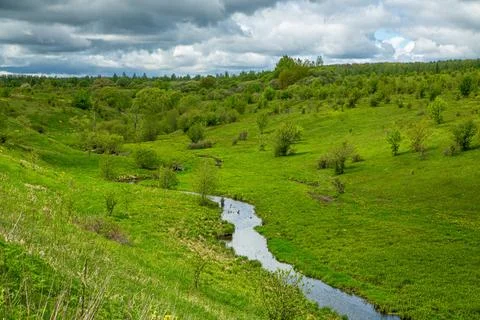 Tranquil scene with greenery, stream, cloudy skies perfect for relaxing and Stock Photos