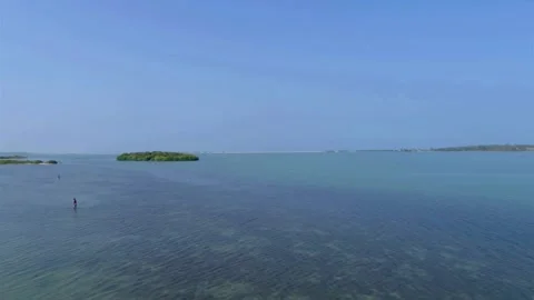 A tranquil sea surrounds a small island under a clear blue sky Stock Footage 312679765