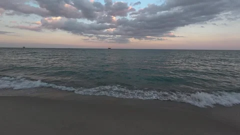 Tranquil sea waves rolling onto the sandy beach at sunset with dramatic clouds Stock Footage 317751078