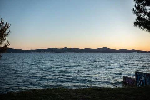 Tranquil Seascape at Dusk with Pine Tree and Graffiti Wall in Zadar Photo Фото
