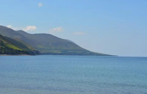 Tranquil Seascape With Gentle Waves and Serene Mountains on the Horizon Stock Photos