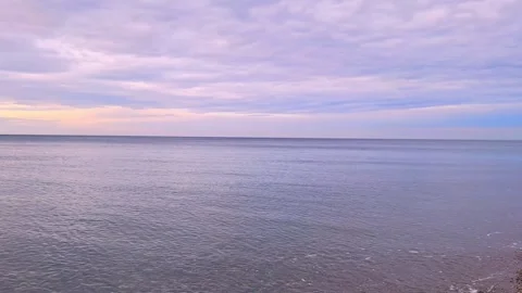 Tranquil seascape with gentle waves lapping against sandy shoreline at dusk Stock Footage 328009837