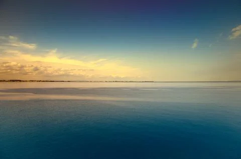 Tranquil seascape under a clear sky. The water reflects gentle clouds Stock Photos