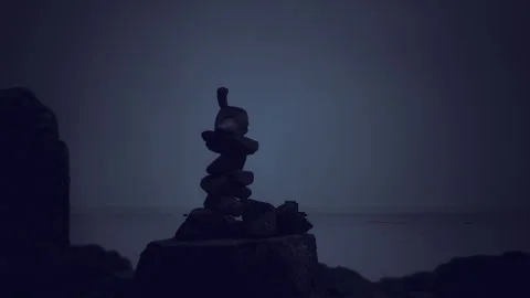 Tranquil seaside setting featuring constructed cairn and fading blue horizon Stock Footage 341573066