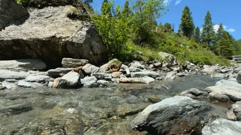 Tranquil Slow Motion Stream Flowing Amidst Rocky Landscape in the Austrian Al Stock Footage 329557436
