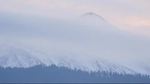 Tranquil Snowcovered Mountain Summit With Hazy Skies And Gentle Cloud Movement Stock Footage 328045113