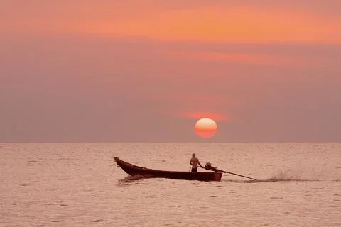 Tranquil Sunset Over the Ocean featuring Fisherman gracefully paddling in Canoe Stock Photos