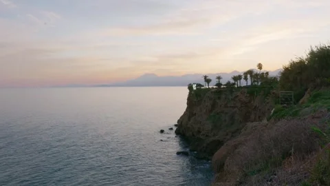 Tranquil sunset over ocean with palm trees and distant terrain Video stock 331556885