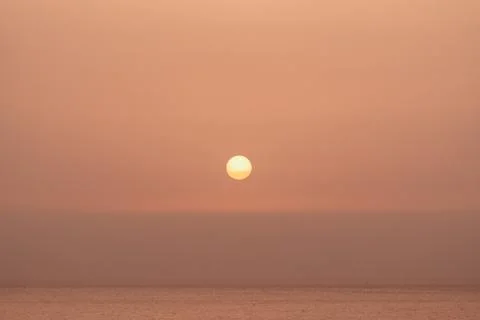 A tranquil sunset over the ocean reflecting soft colors in the calm evening sky Stock Photos