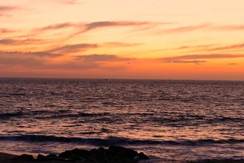 Tranquil sunset over the sea with soft pink and orange clouds Stock Photos
