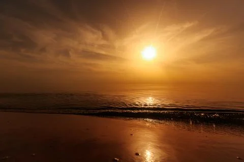 Tranquil sunset over a smooth beach shoreline with gentle waves and golden. Stock Photos