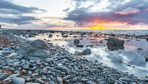 Tranquil Sunset Reflection on Rocky Beach Foto stock