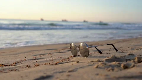 A Tranquil Sunset Scene on the Beach Featuring Stylish Sunglasses Resting in Stock Footage 346742343