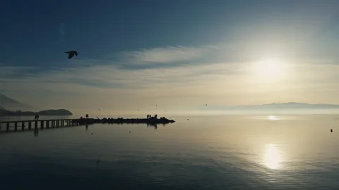 Tranquil sunset scene with a pier extending into the still lake - Ohrid Stock Footage 304912297
