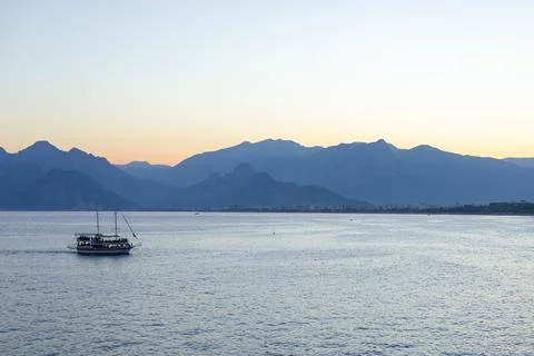 Tranquil sunset view over the mountains with a boat sailing in the peaceful Stock Photos