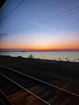 Tranquil sunset view from a train by the ocean Stock Photos