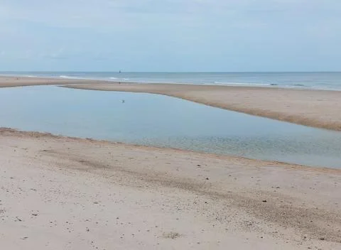 Tranquil tide pool on sandy beach with calm sea in Hua Hin Stock Photos