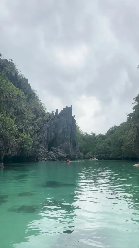 Tranquil turquoise waters reflect the surrounding cliffs and lush greenery Stock Footage 313282557