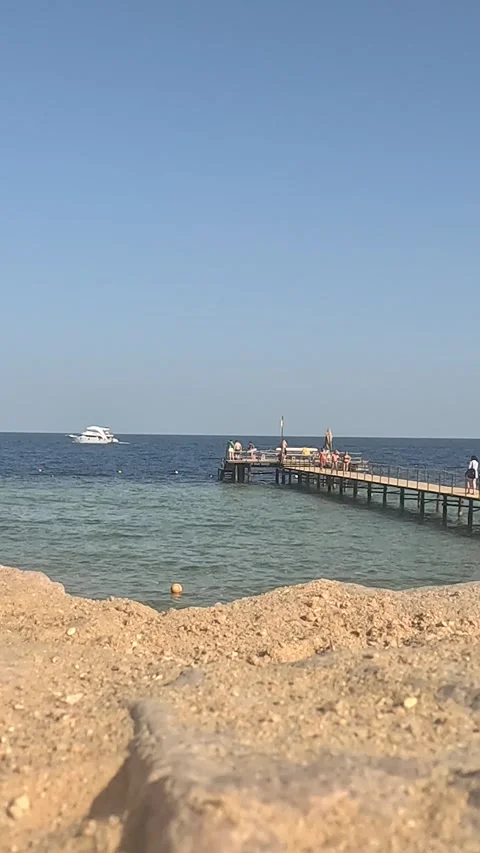 A tranquil view of a clear blue ocean from a sandy beach, showcasing a wooden Video stock 330097354