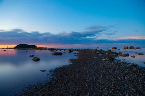 Tranquil view of sunset with stoned path to the small lonely island on shore of Stock Photos