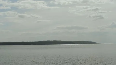 A tranquil view of water and a distant island under a cloudy sky, perfect for Video stock 309817025