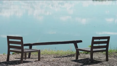 Tranquil view of the wooden table and chairs along the lake shore Stock-Footage 213306540