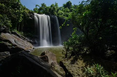 Tranquil waterfall cascading over rocks into lush green forest pool in natu.. Stock Photos