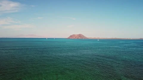 Tranquil waters embrace a distant island in bright daylight Stock Footage 307642579