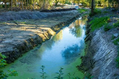 A tranquil waterway flows gently through a peaceful landscape, reflecting t.. Stockfoto's