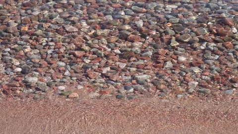 Tranquil waves lapping along the shore of small pebbles Stock Footage 260938985