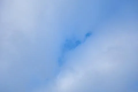 Tranquil white clouds float across a blue sky, creating a peaceful atmosphere Stock Photos