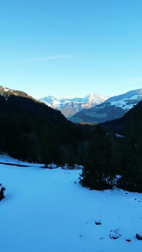 Tranquil winter mountain in the Alps snow covered fields distant peaks under a Vídeo Stock 334117906
