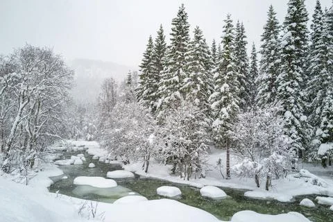 A tranquil winter scene with a river flowing through snowy surroundings, li.. Foto stock