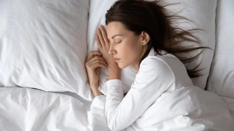 Tranquil young lady enjoying good night rest in comfortable bed. Stock Photos