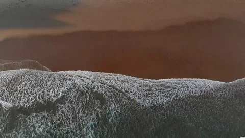 Tranquility concept. Foamy waves of a green sea rolling to a brown coast. Top Stock Footage 100356800