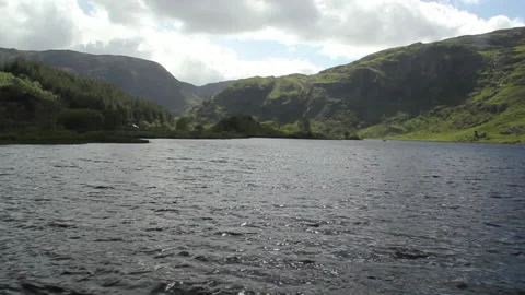 Tranquol lake, dramatic hills and a passing tourist car in the distance Stock Footage 230988961