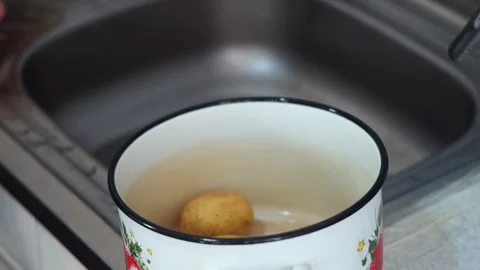 Transfer of washed potato roots to a white enamel saucepan by the hands of .. Stock Footage 276645073