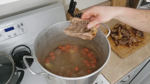 Transferring previously roasted roasted Duck into large pot containing broth Stock Footage 104247088