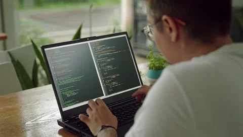 Transgender developer programs on laptop at plant-filled workspace. Codes Stock Footage 270233433