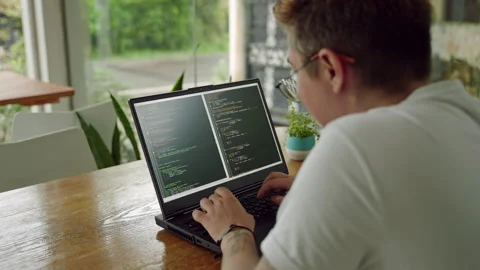 Transgender programmer codes on laptop in coworking space, focused on debugging Stock Footage 268734432
