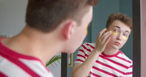 Transgenger guy does beauty routine front  mirror wearing cleaning eye patches Stock Footage 134966700