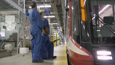 Transit workers inspecting light rail train in maintenance facility Video stock 221033716