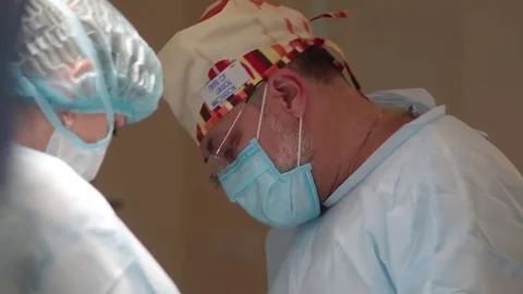 The transition of the camera from the face of the surgeon on his bloody hands Video stock 70808687